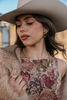 Gold-dipped marbling stone necklace worn with a western hat and patterned top.