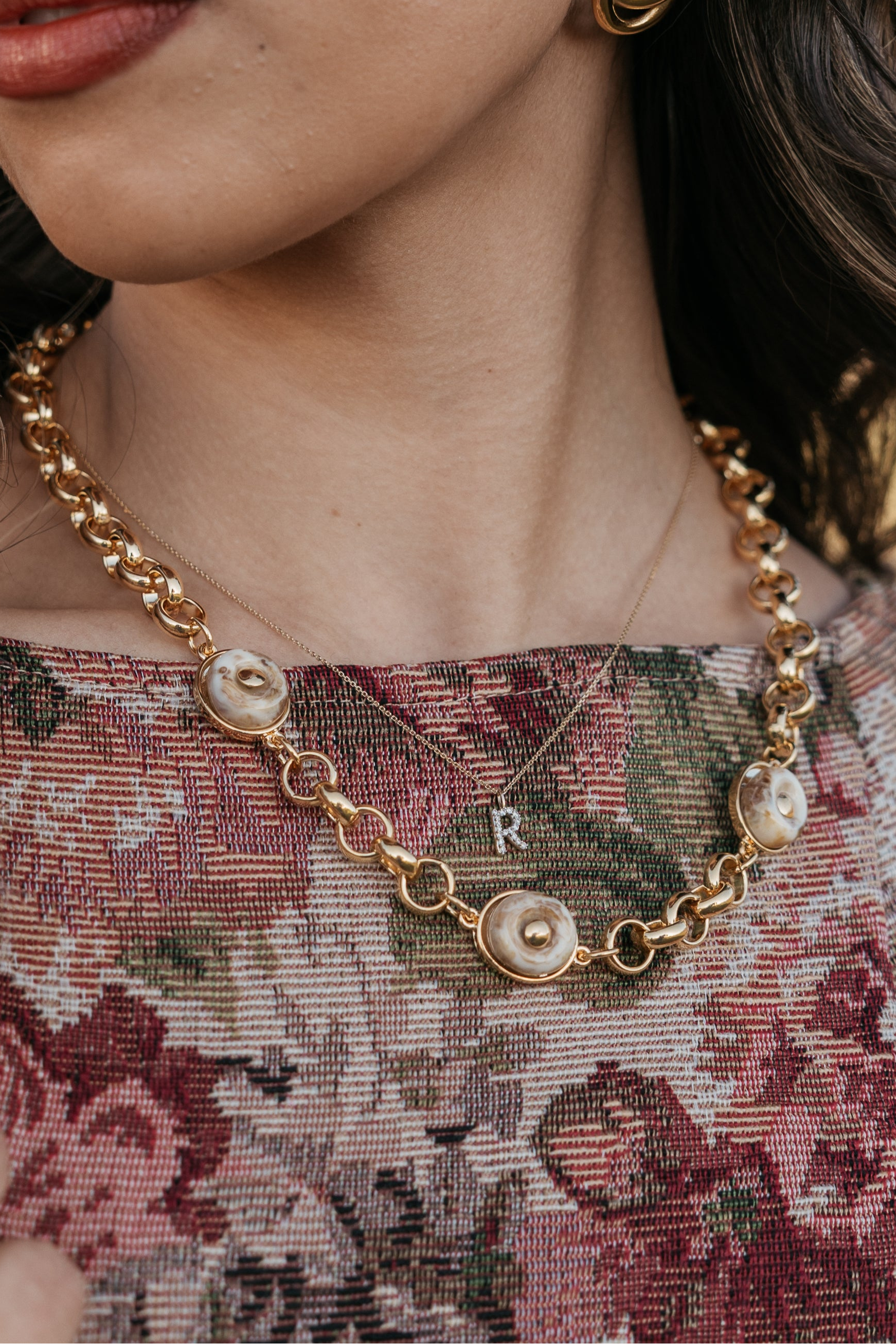 Close up. Gold-dipped marbling stone necklace worn with a western hat and patterned top.