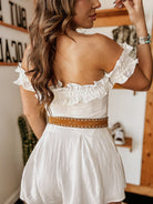 Woman in white off-shoulder ruffle dress with brown western belt, boho cowgirl outfit