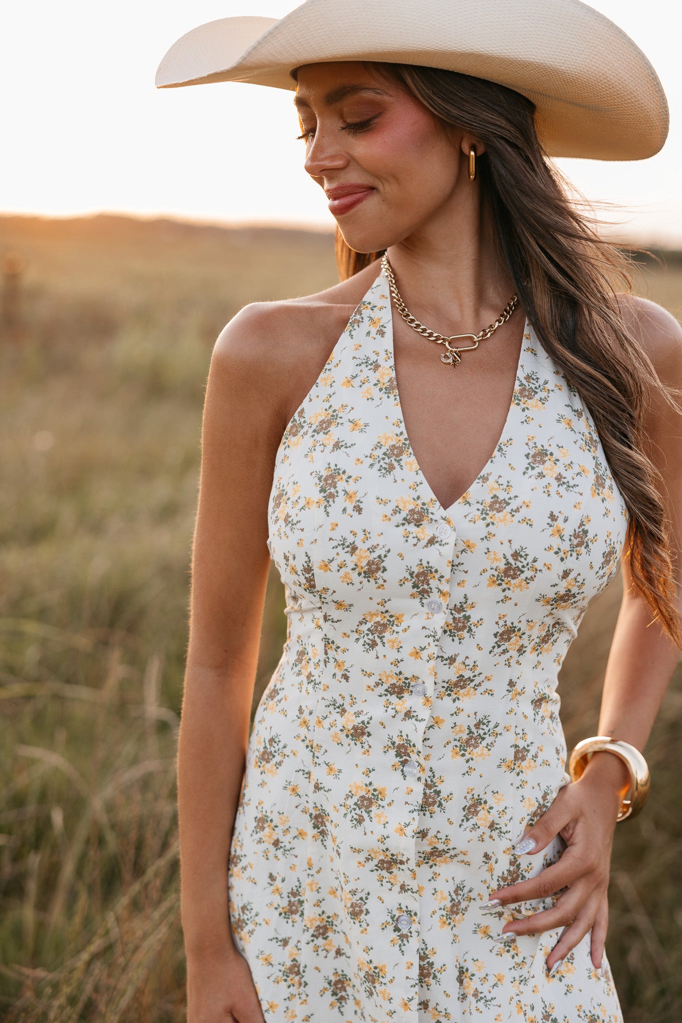 Woman wearing a floral dress and wide-brimmed hat in a field