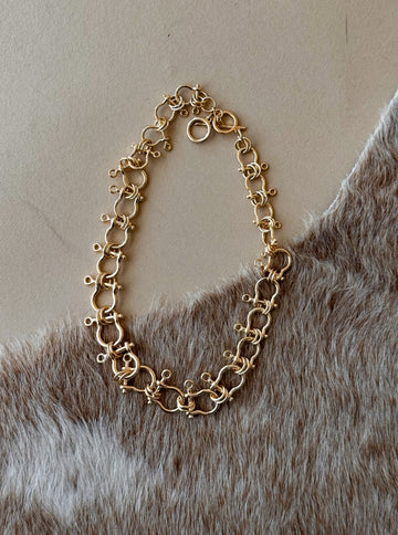 Gold carabiner chain link necklace on textured background