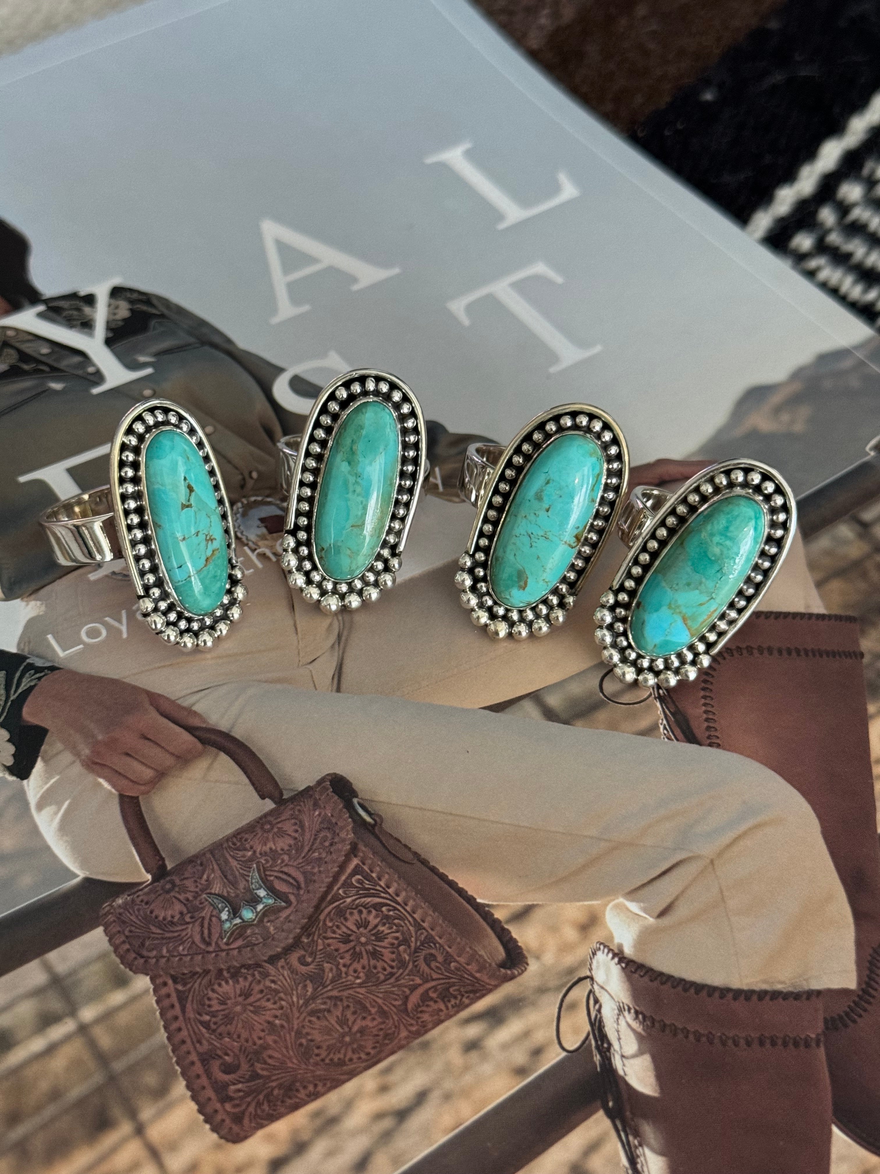 Four silver rings with oval turquoise stones on western fashion magazine, cowgirl style accessories
