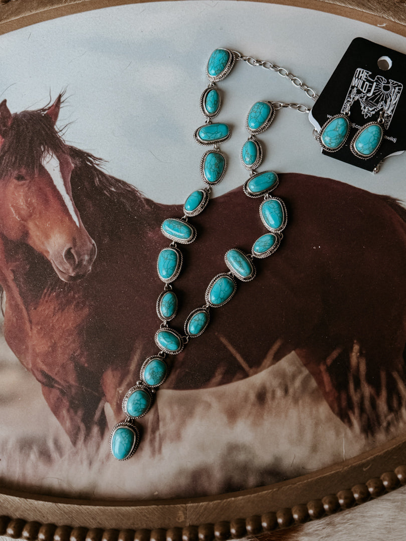 Thunderbird pendant chain necklace displayed on wooden slab with serape fabric underneath - The Wild J