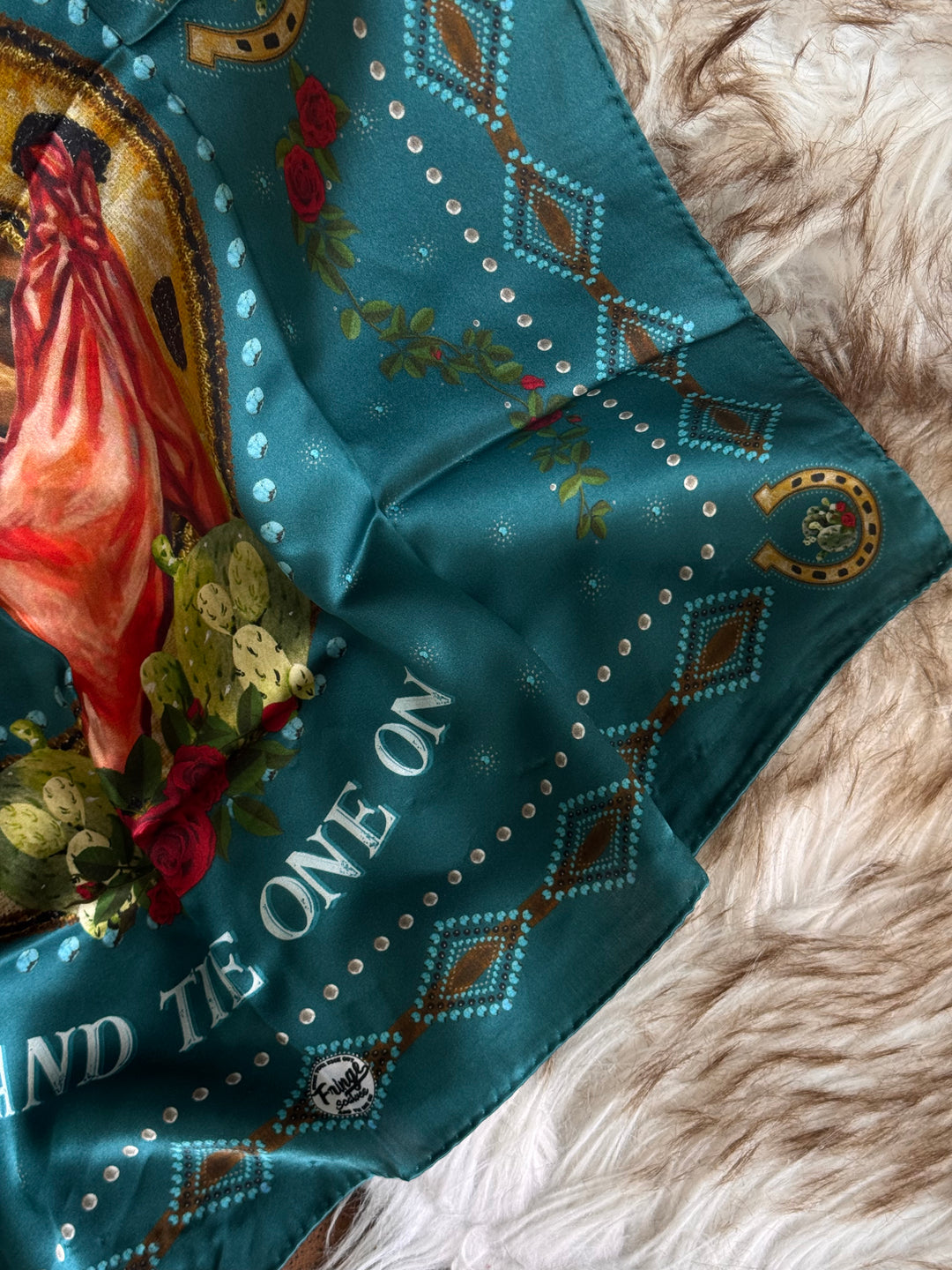 Teal bandana with decorative patterns and text on a textured surface
