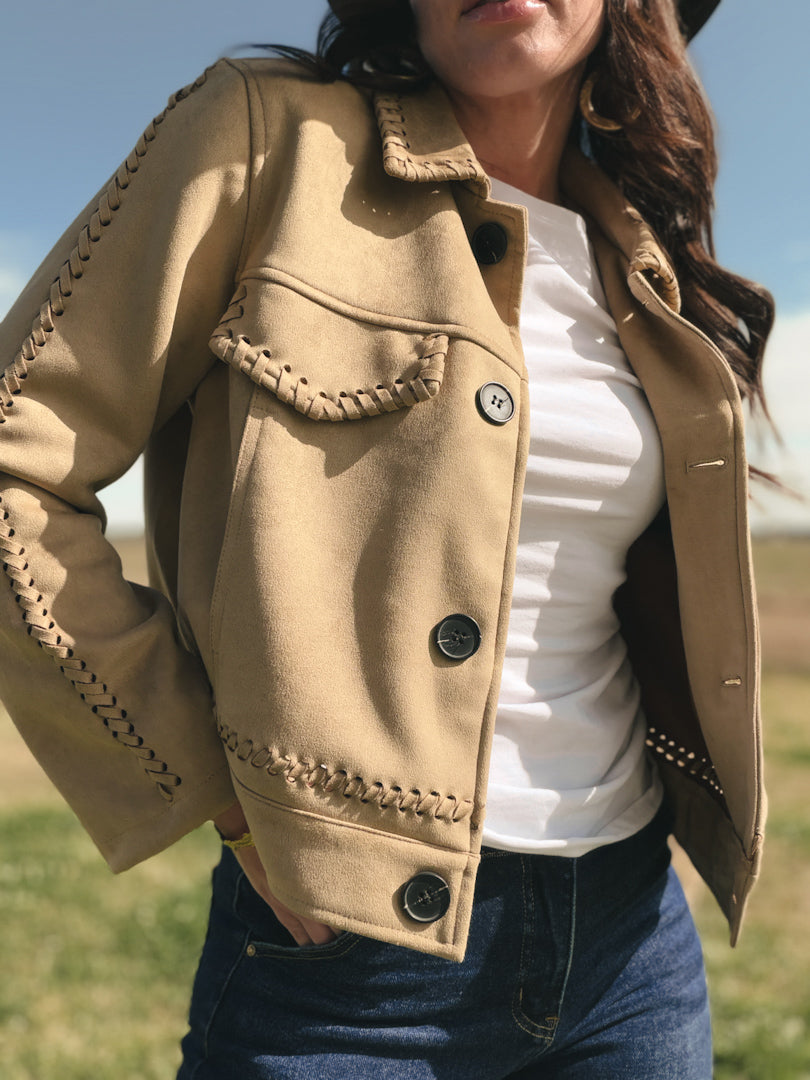 Person wearing a beige jacket with braided details outdoors
