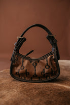 Thunderbird pendant chain necklace displayed on wooden slab with serape fabric underneath - The Wild J