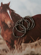 Stacked western silver beaded bracelets on a vintage horse background, boho jewelry