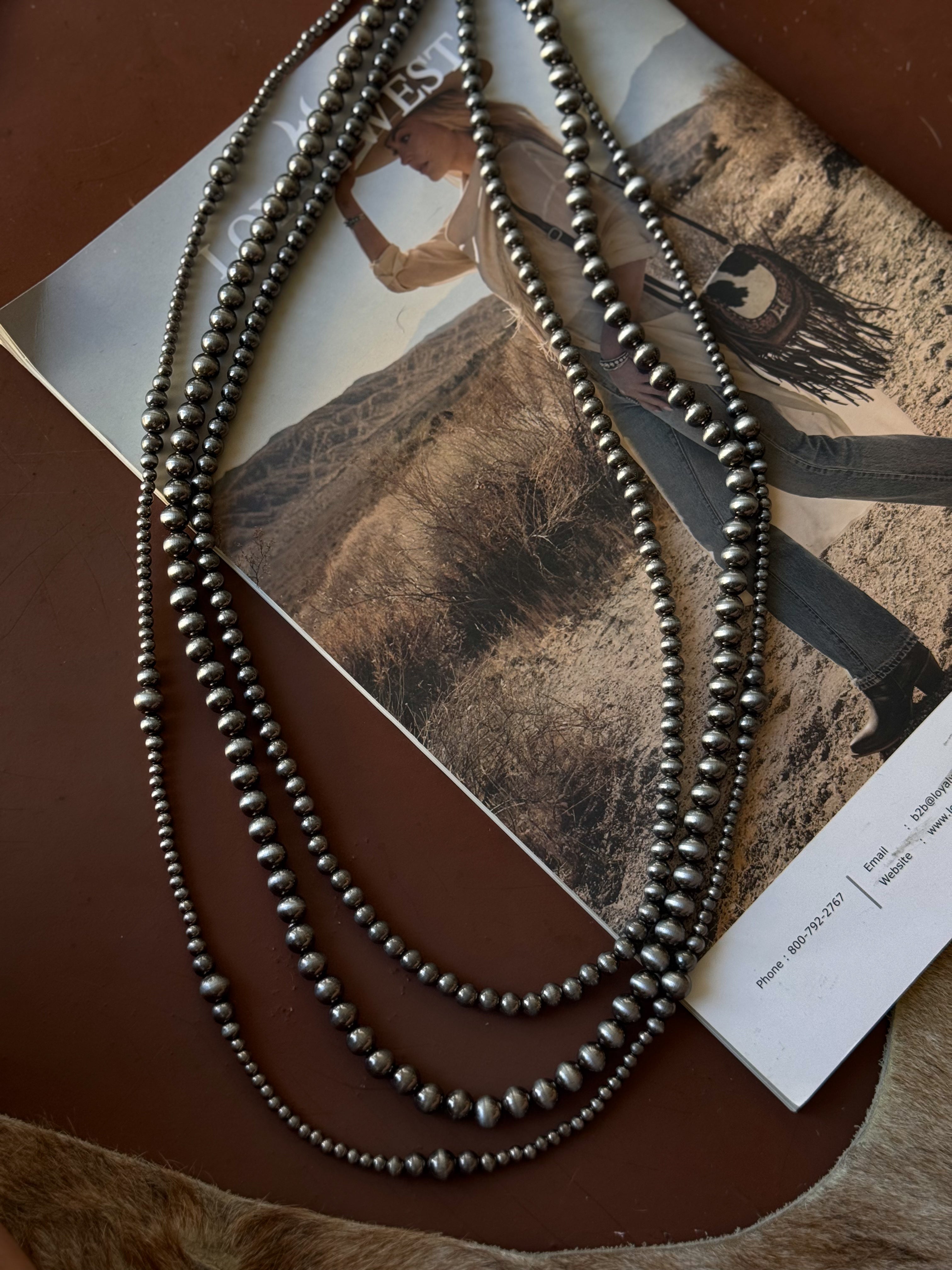 Thunderbird pendant chain necklace displayed on wooden slab with serape fabric underneath - The Wild J