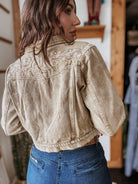 Woman wearing western cropped denim jacket with floral embroidery and high-waisted jeans