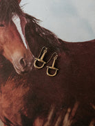 Gold western stirrup earrings on a horse background, cowgirl jewelry, western accessories