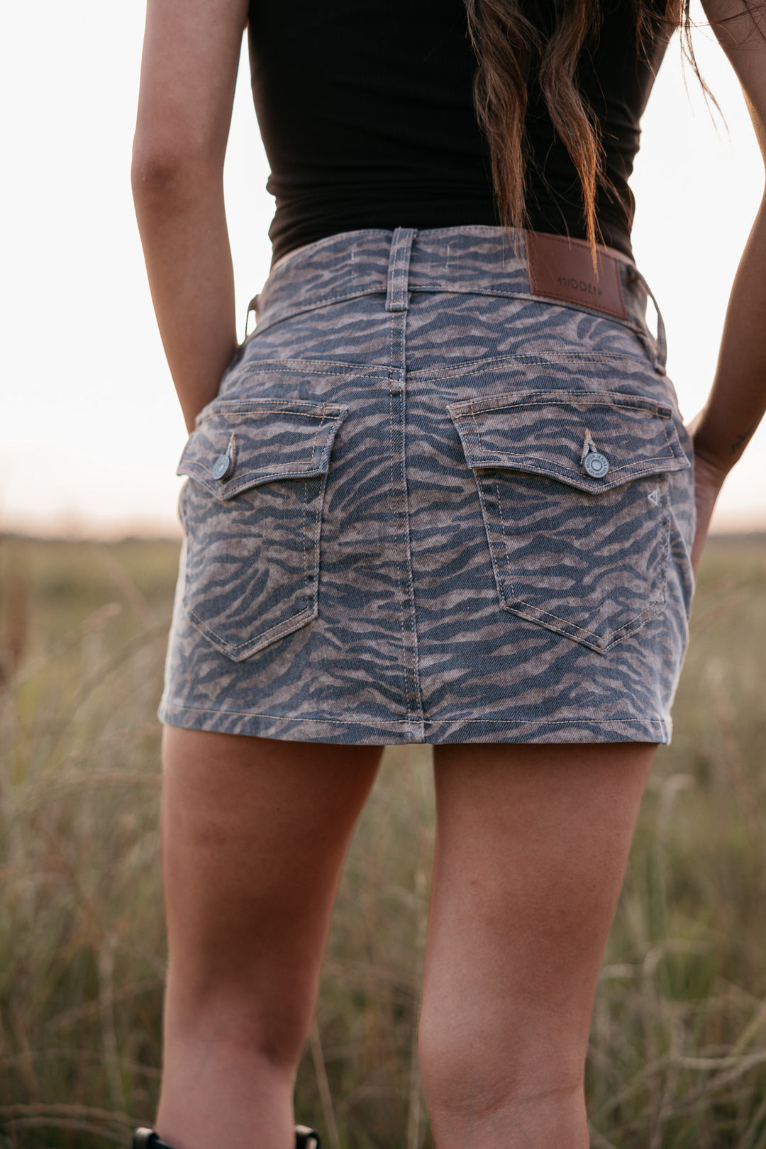 Person wearing a tiger-striped skirt in a grassy field
