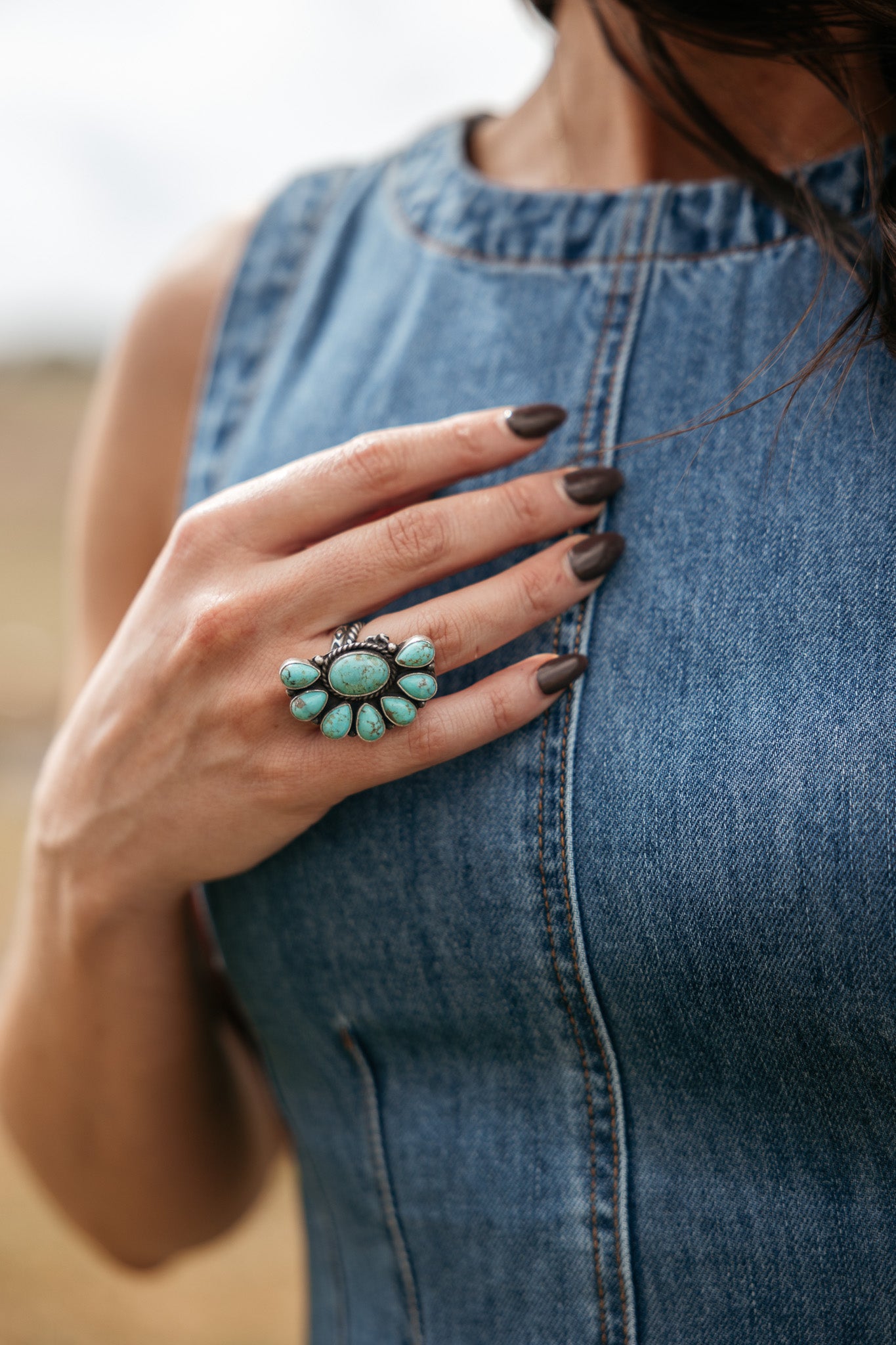Woman wearing a turquoise western ring with denim sleeveless dress, boho cowgirl style