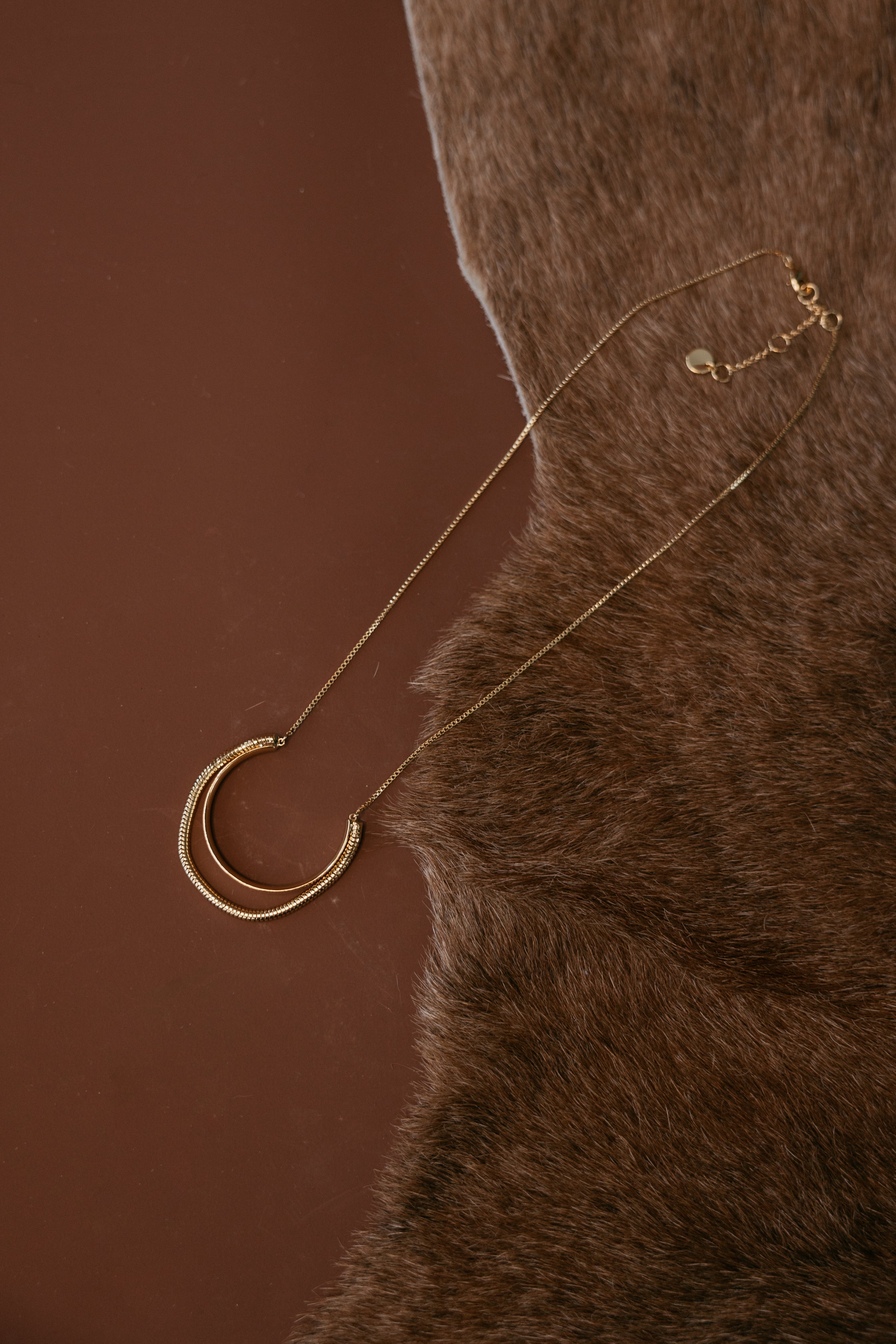 Thunderbird pendant chain necklace displayed on wooden slab with serape fabric underneath - The Wild J