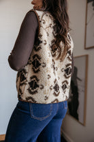 Woman wearing sherpa western print vest, ribbed brown top, and blue jeans