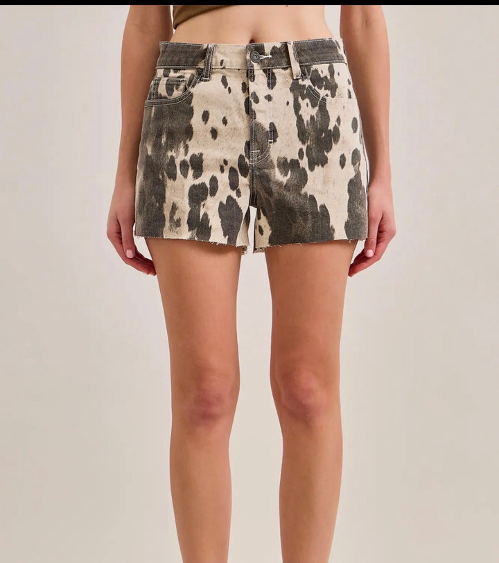 Cow print shorts worn by a person on a plain background