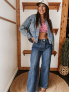 Woman in wide leg jeans, denim jacket, and cowgirl hat with western boho style indoors