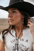 Thunderbird pendant chain necklace displayed on wooden slab with serape fabric underneath - The Wild J