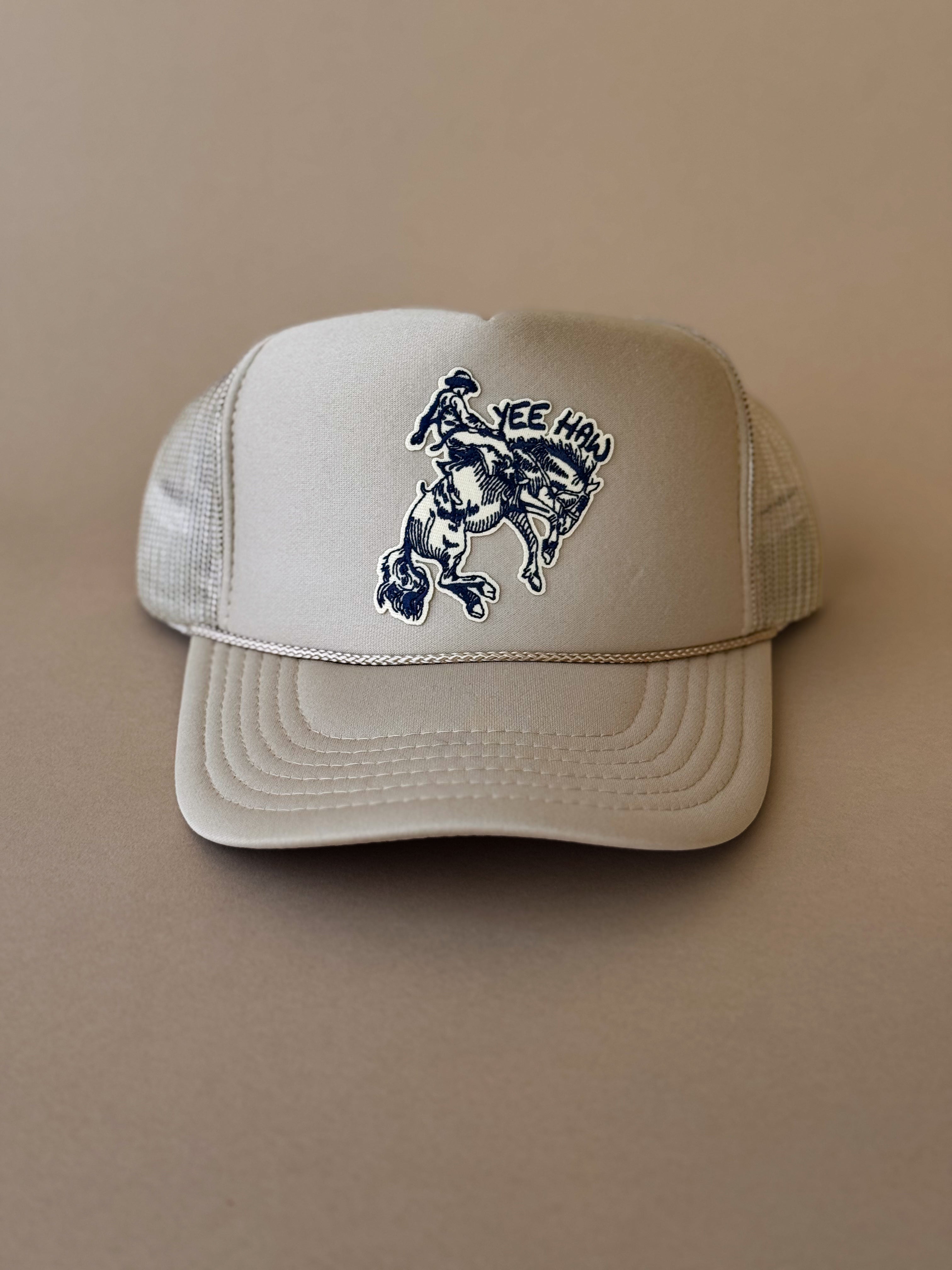 Beige western trucker hat with cowboy riding horse and 'Yee Haw' graphic on front panel.