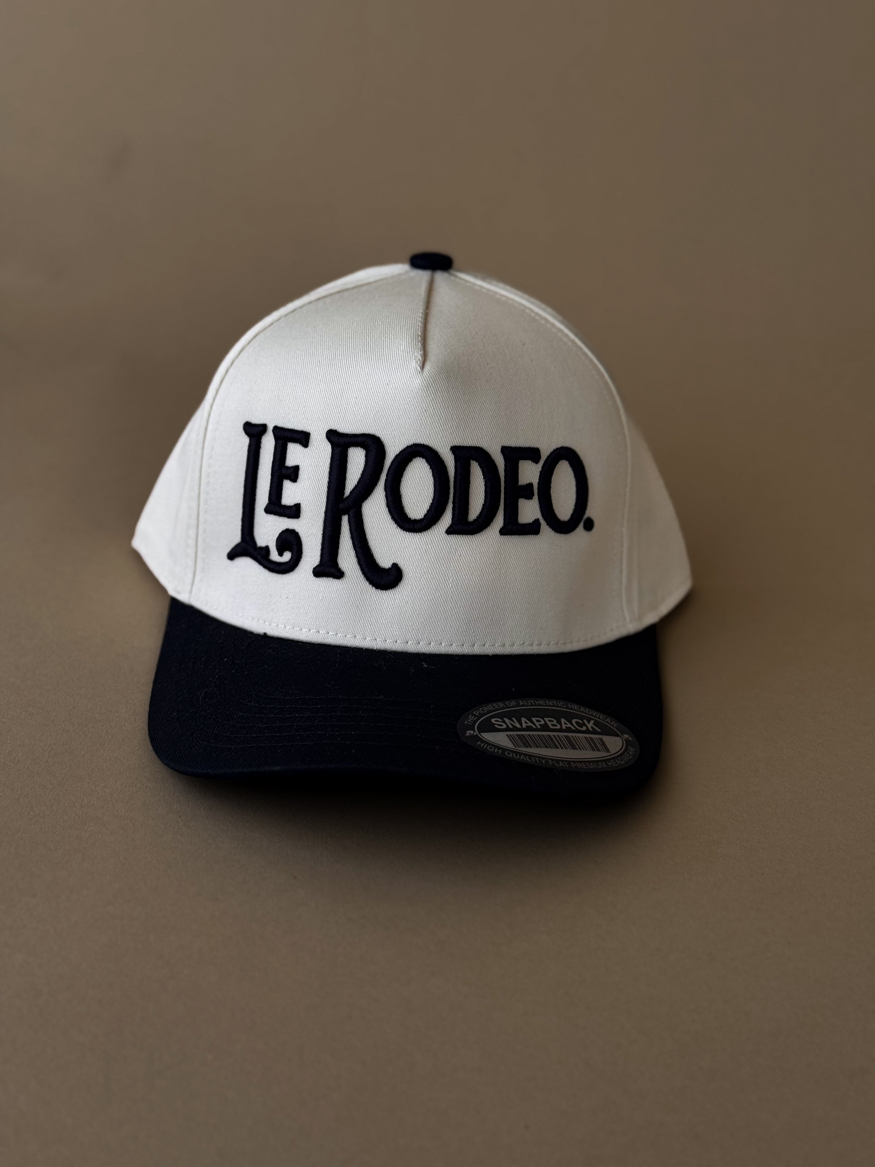 Black and white snapback hat with 'Le Rodeo' embroidered, western rodeo style accessory