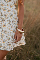 Person wearing a floral dress with a blurred natural background