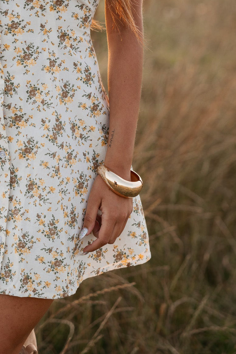 Person wearing a floral dress with a blurred natural background