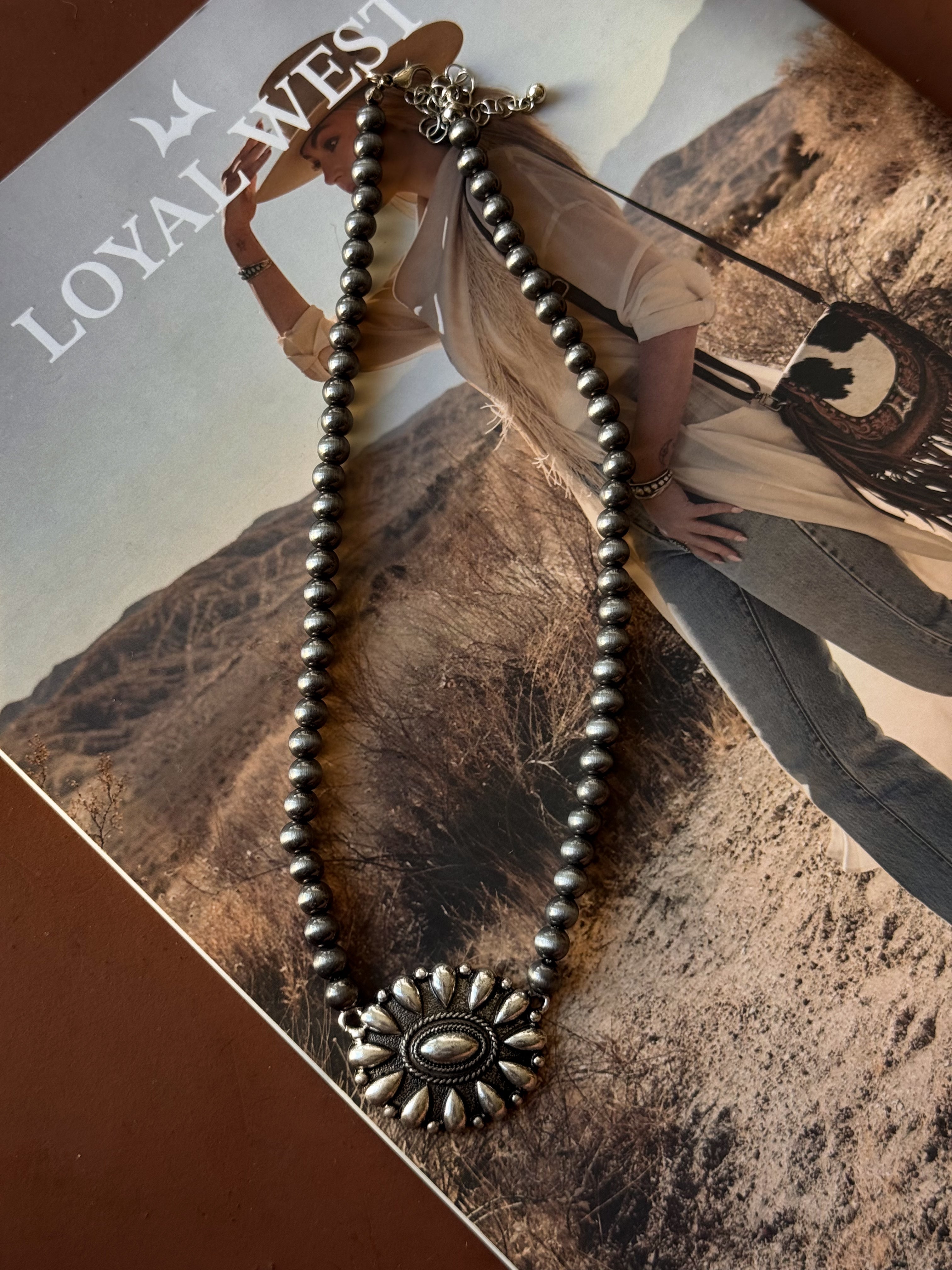 Thunderbird pendant chain necklace displayed on wooden slab with serape fabric underneath - The Wild J