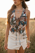 women wearing tie front halter top with horse pattern and a ivory skirt with buckles standing in a field. 