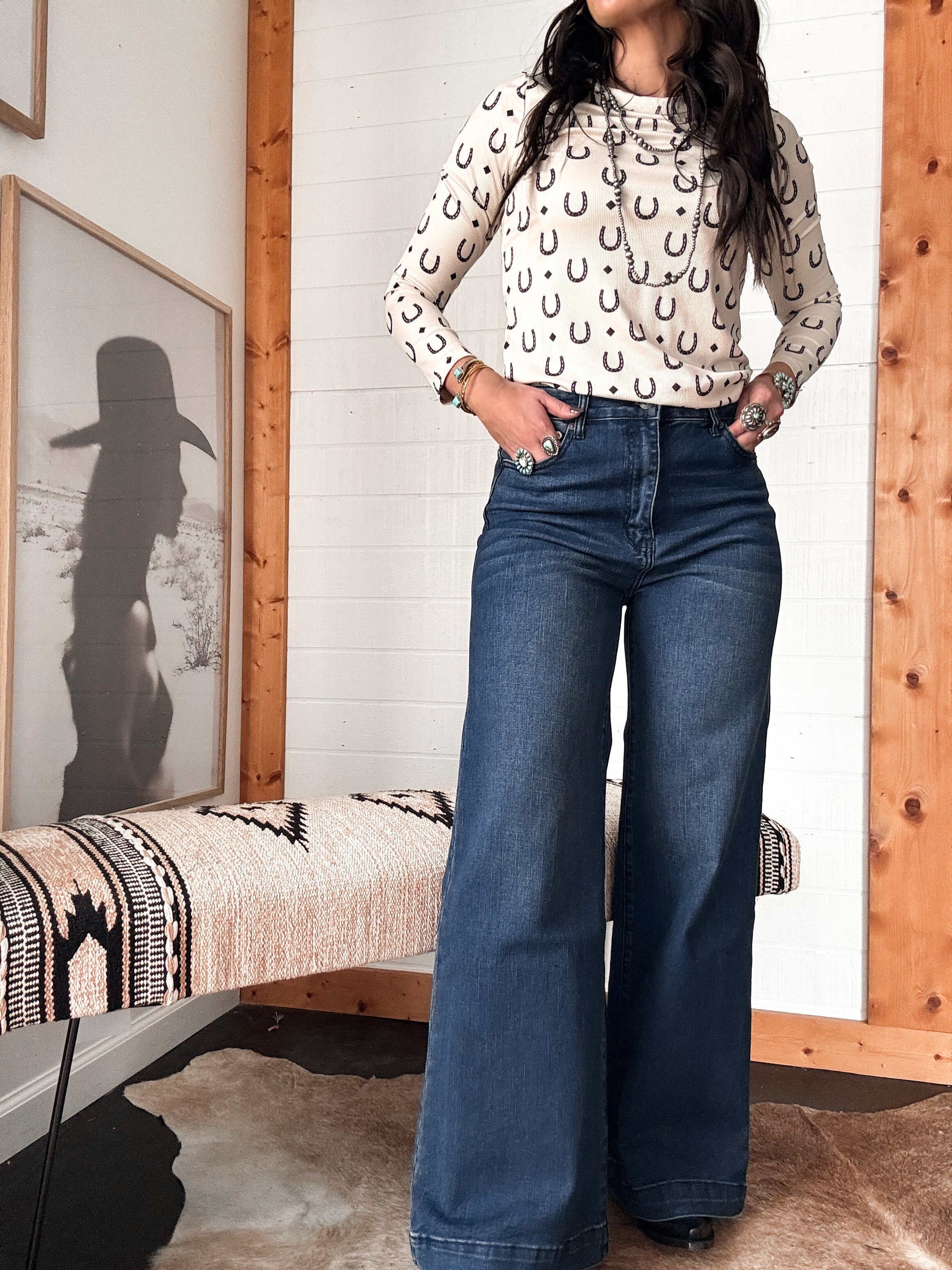 Woman in western boho outfit wearing horseshoe print long sleeve top and wide-leg jeans