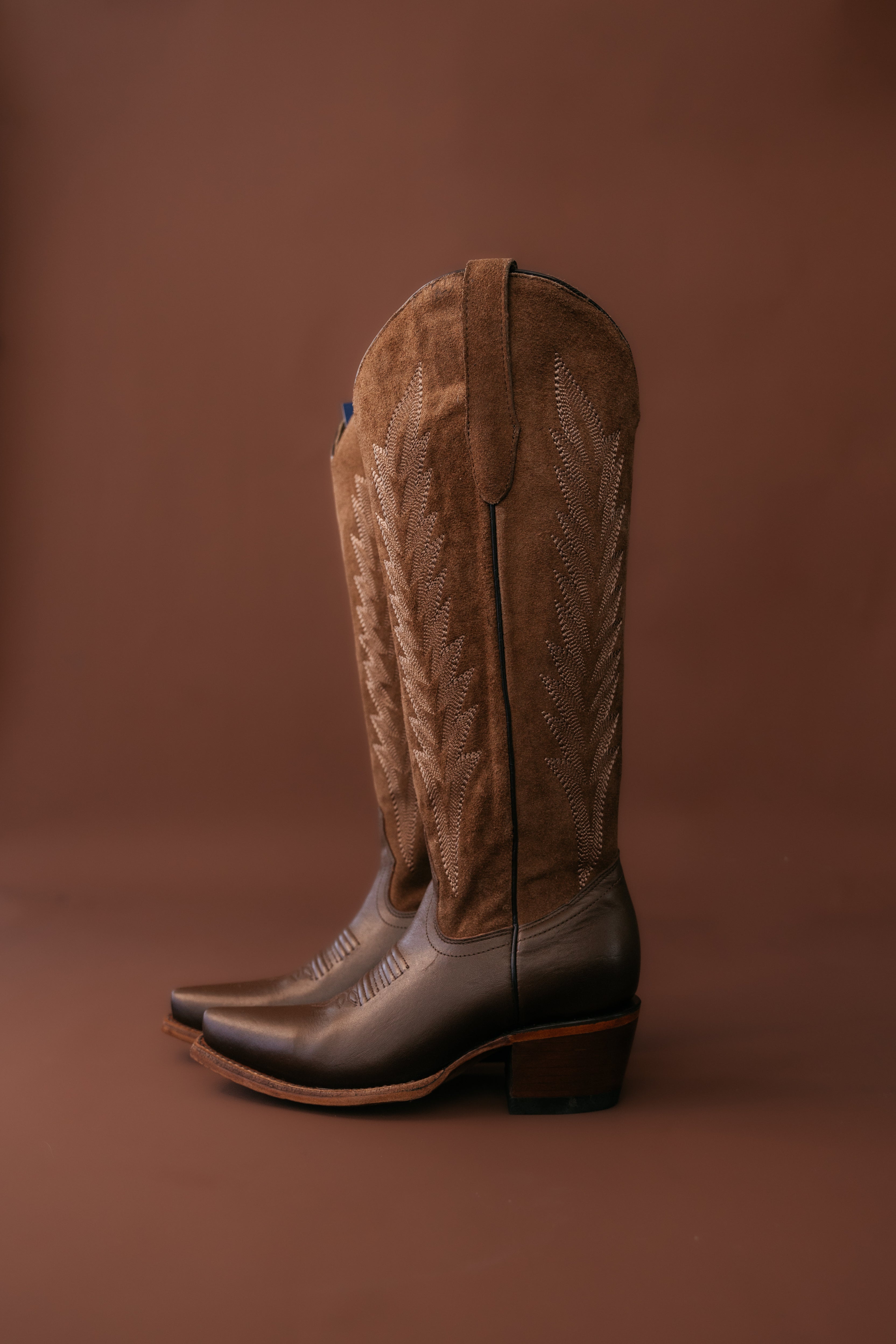 brown suede western cowboy boots with embroidery on brown background