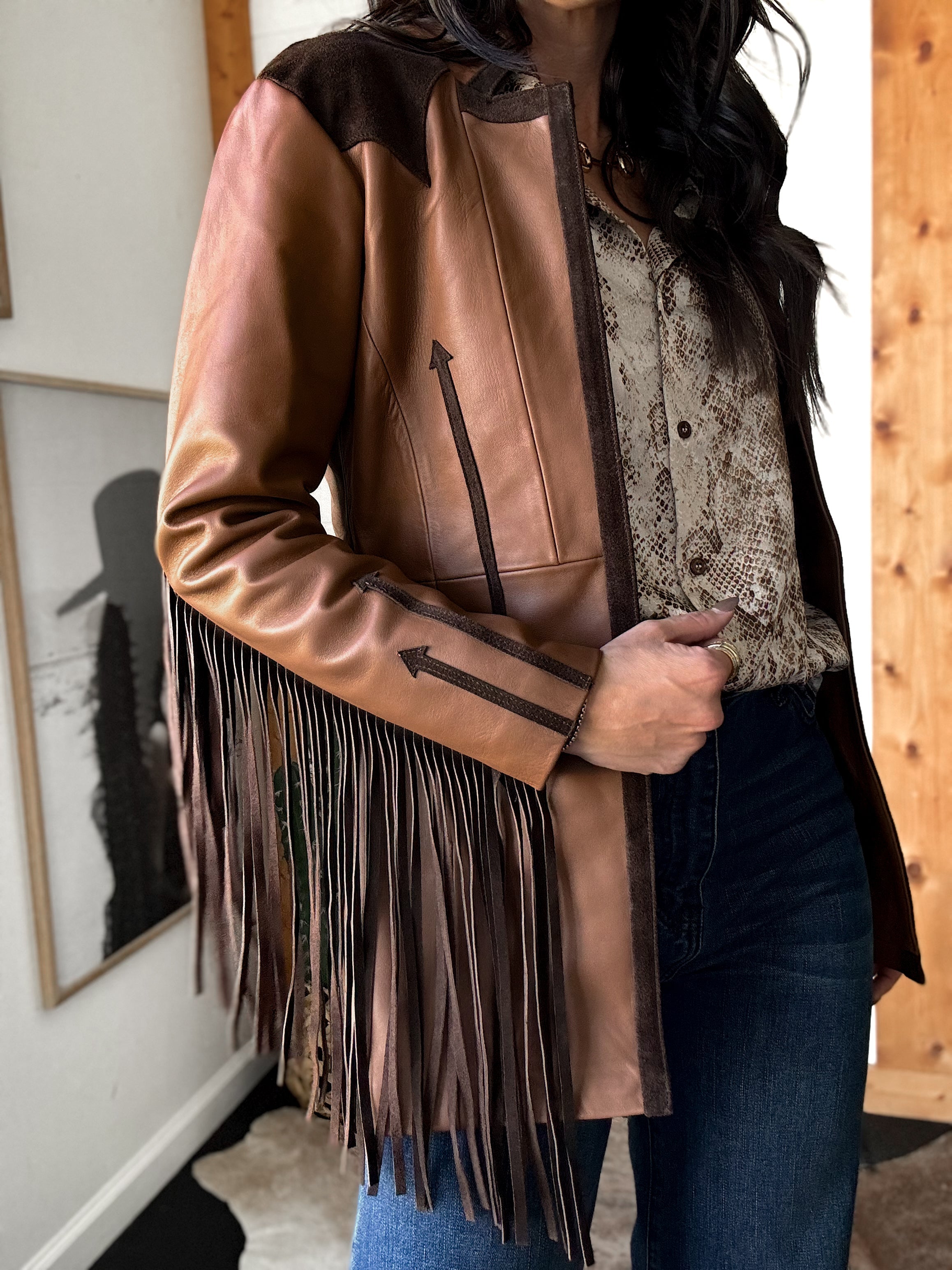 Woman wearing western fringe leather jacket, snakeskin blouse, blue jeans, cowgirl style