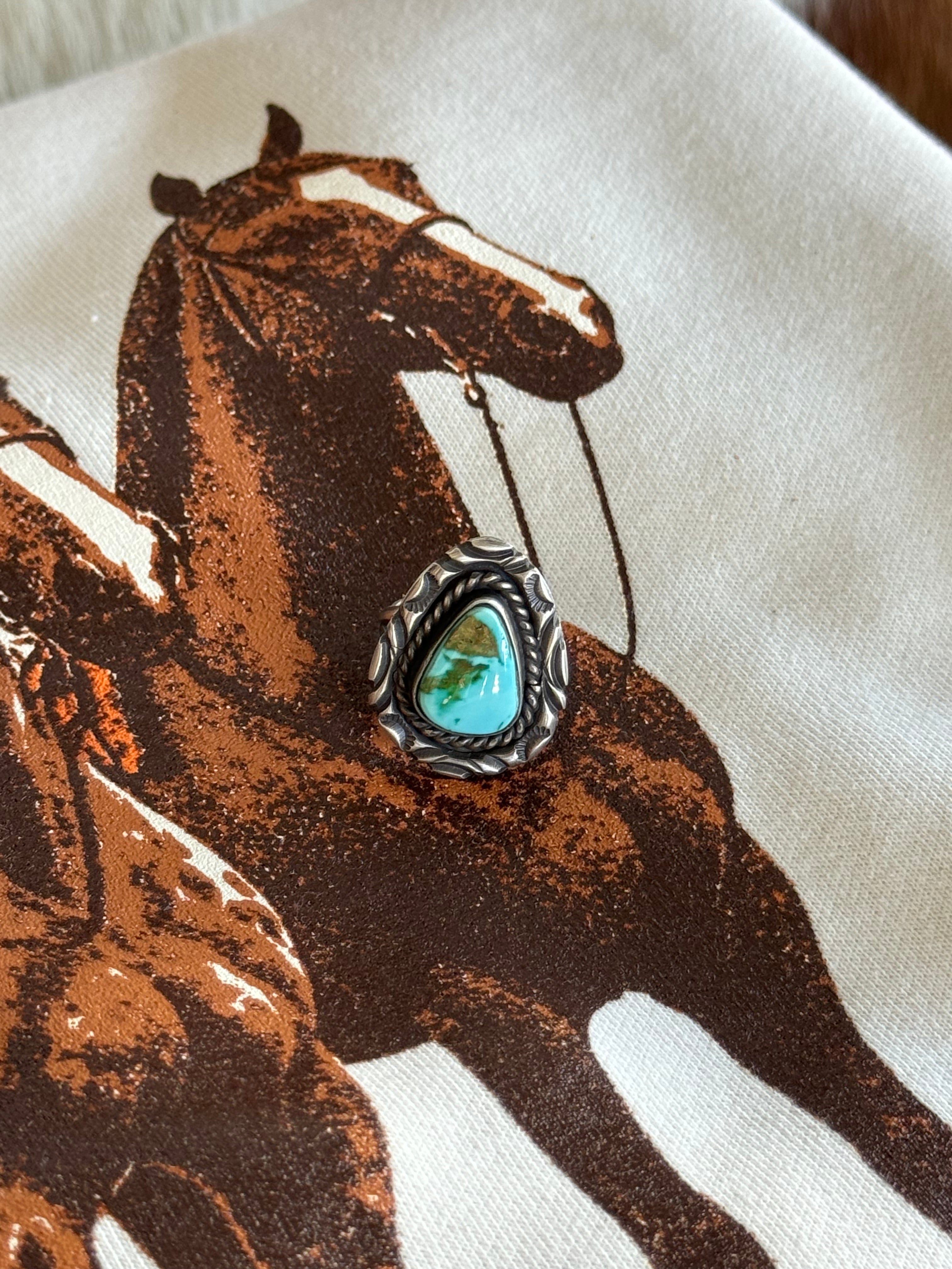 Turquoise western boho ring with silver detailing on a graphic horse print background
