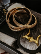 Gold western bangles on a cowhide purse with decorative gold hardware