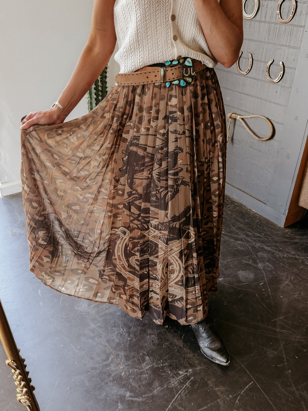 Person wearing a patterned skirt and white top in a room with decorative elements.