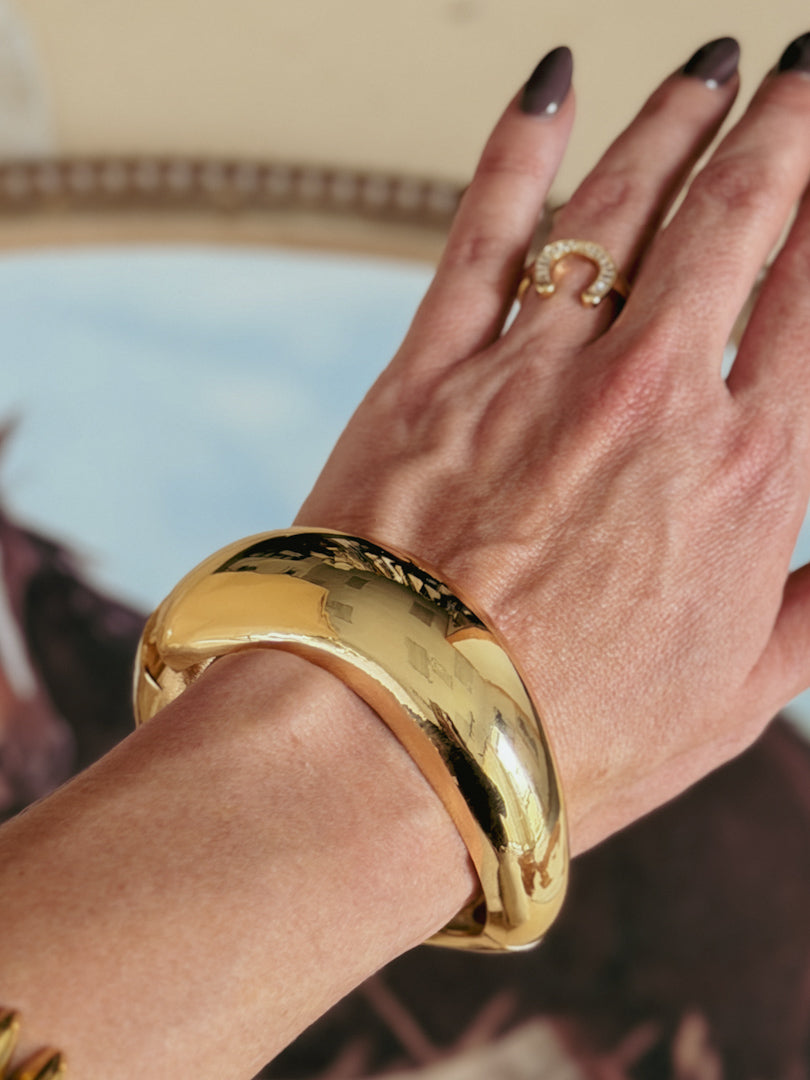 Gold statement bracelet and western horseshoe ring on hand, boho western jewelry style