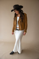 Woman in cowgirl hat, brown suede jacket, white maxi skirt, Western boho outfit