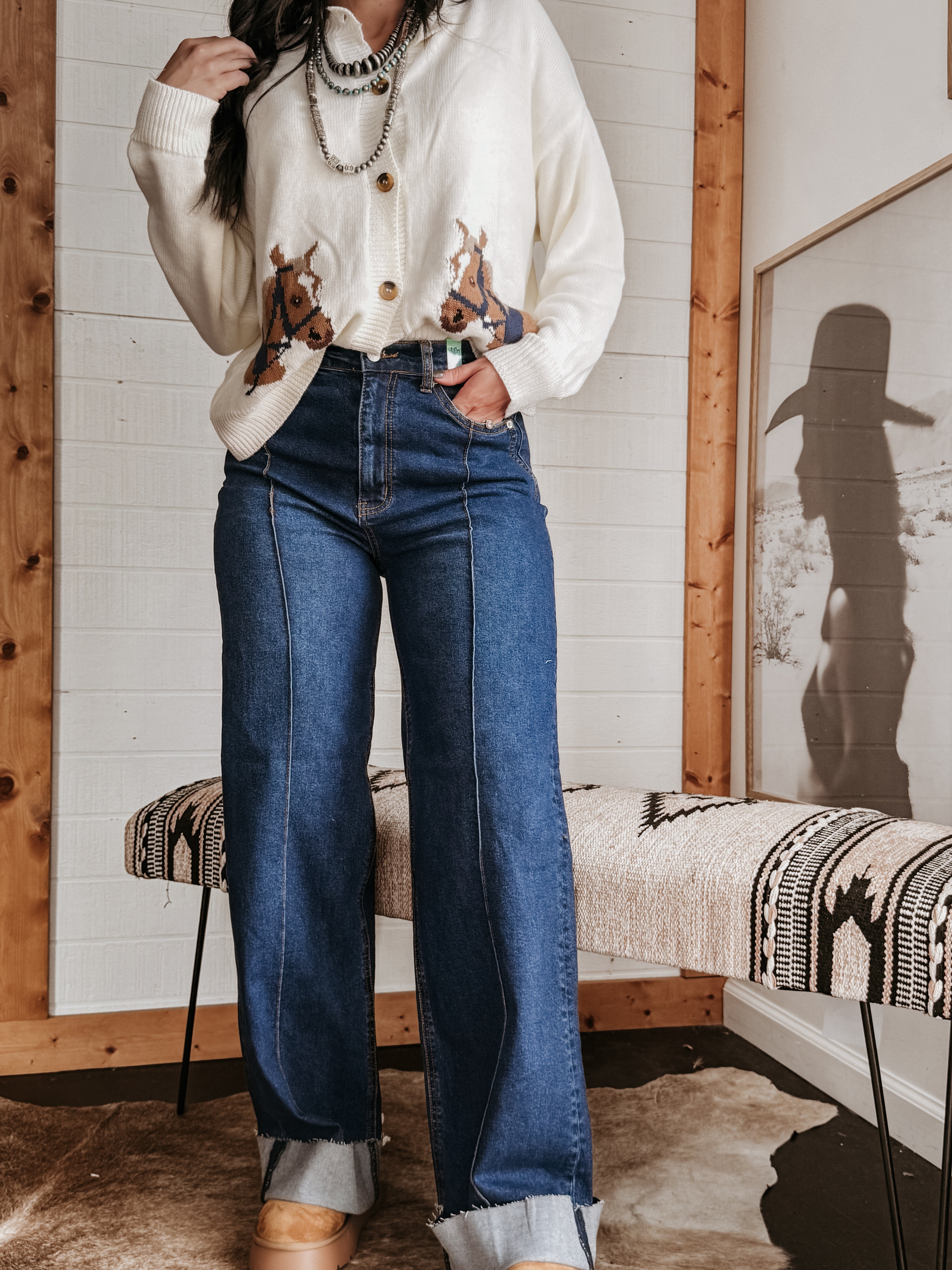 Woman in western boho outfit with horse print sweater, chunky necklace, and wide leg jeans