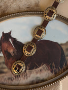 Western concho belt with engraved gold accents on brown leather, rustic cowgirl style