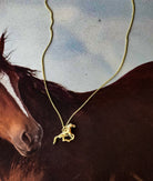 Thunderbird pendant chain necklace displayed on wooden slab with serape fabric underneath - The Wild J