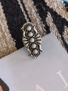 Silver western boho ring with floral engravings on a textured rug background
