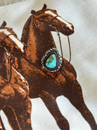 Turquoise western ring with silver engraved setting on cowboy horse print fabric