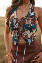 women wearing tie front halter top with horse pattern and a Burgundy skirt standing in a field. 