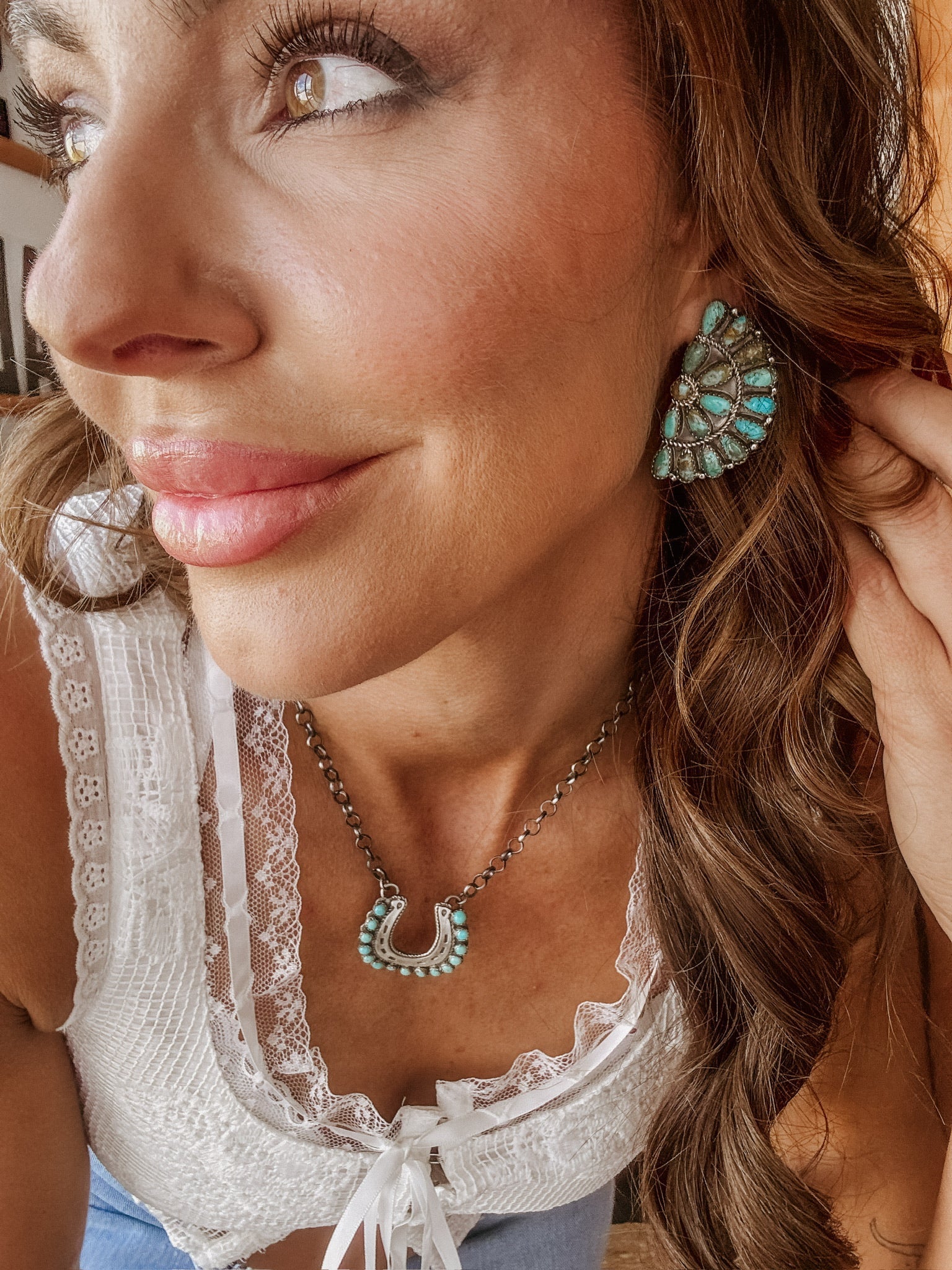 Woman wearing boho western turquoise statement earrings and horseshoe necklace