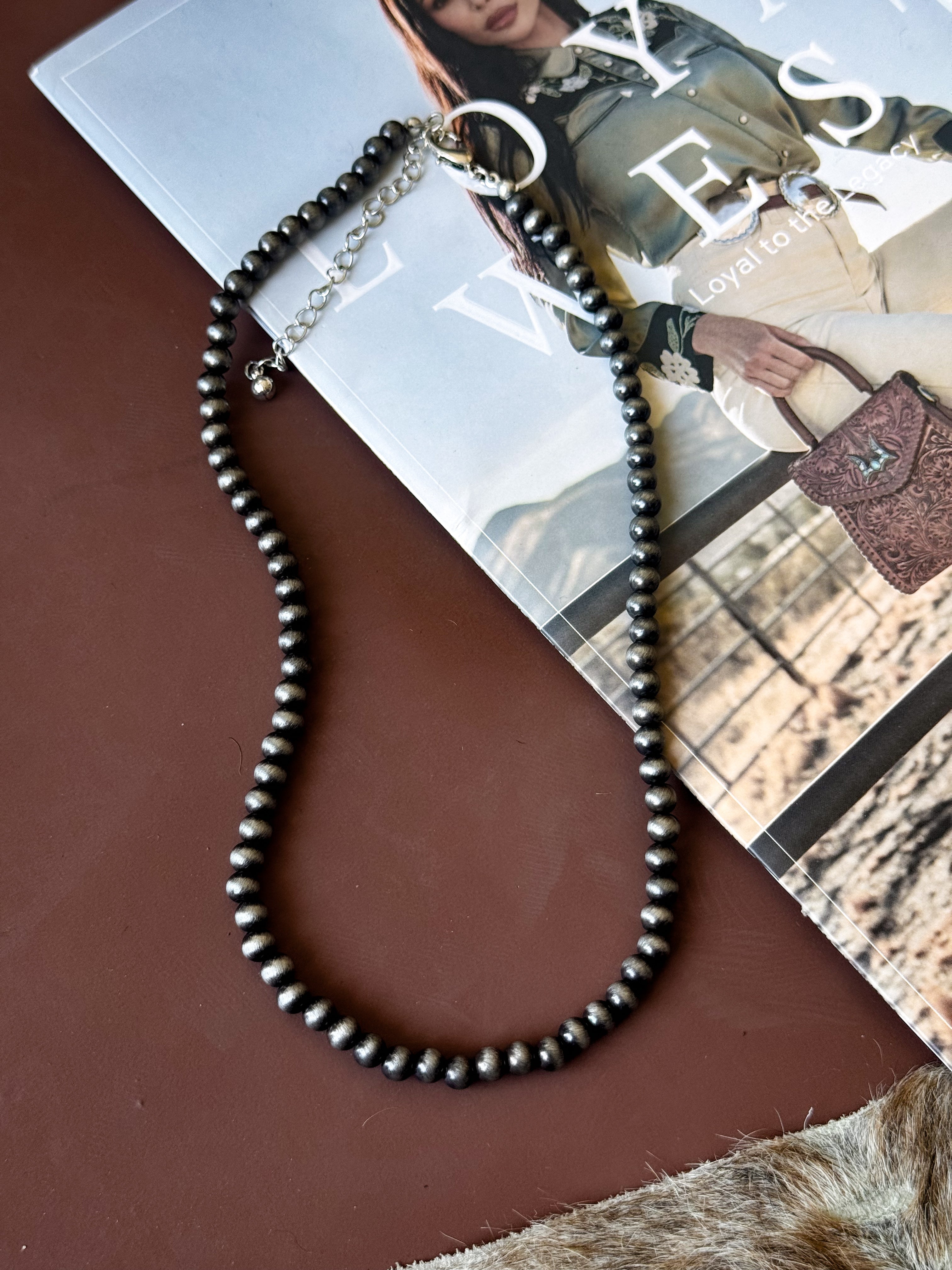 Silver western beaded necklace with adjustable clasp on rustic brown surface, perfect for boho outfits.