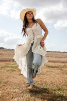Woman in a cowboy hat wearing a boho western ruffle top and jeans in a rustic field