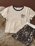 Beige Rodeo Girl ringer tee with black trim and leopard print western skirt on faux fur.