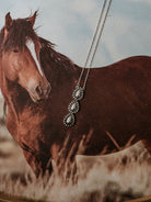 Thunderbird pendant chain necklace displayed on wooden slab with serape fabric underneath - The Wild J