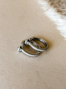 Sterling silver hinged hoop earrings with cubic zirconia accents.