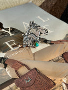 Thunderbird pendant chain necklace displayed on wooden slab with serape fabric underneath - The Wild J