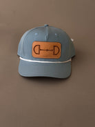 Blue western trucker hat with leather horse bit patch and white rope accent