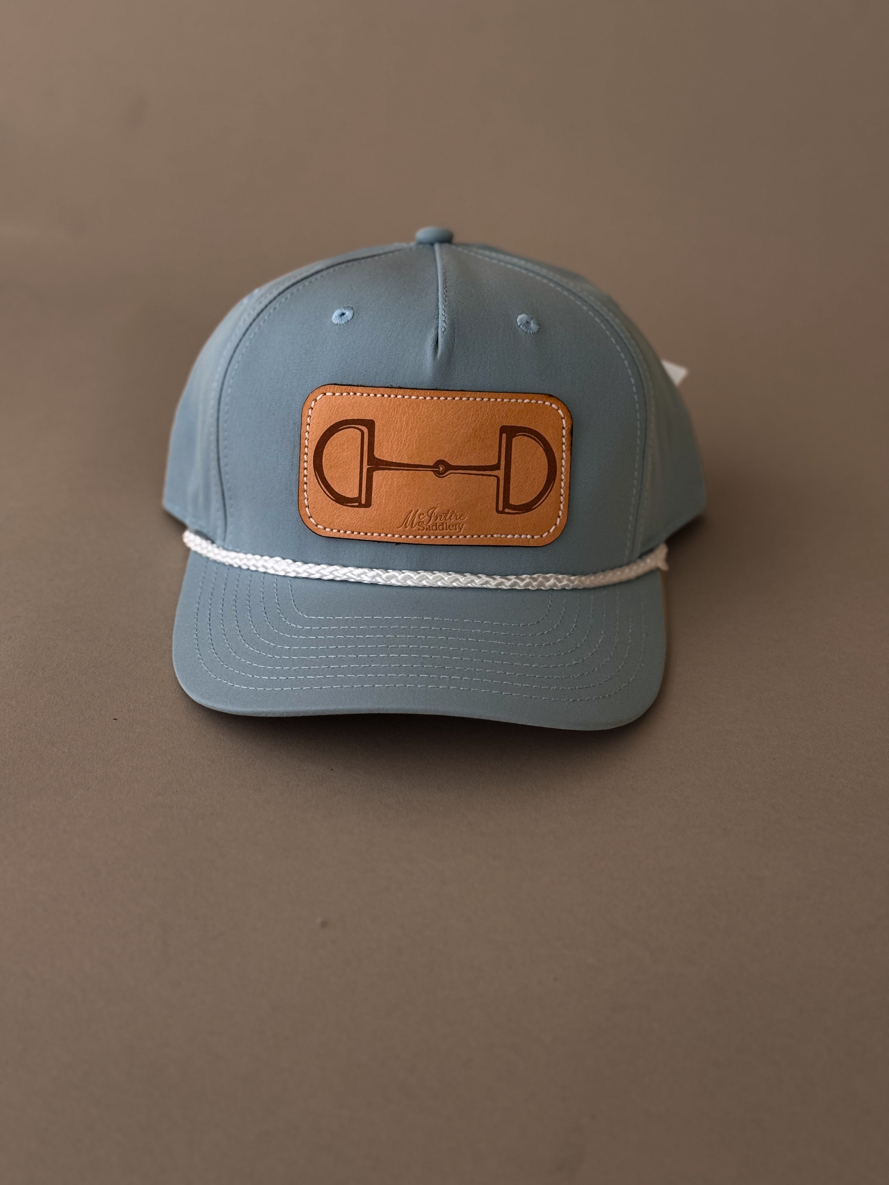 Blue western trucker hat with leather horse bit patch and white rope accent